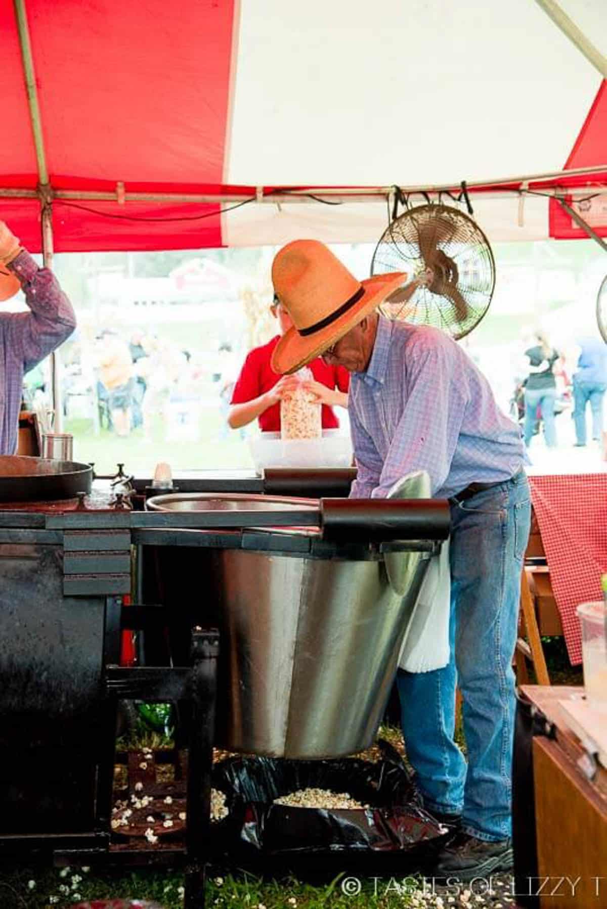 man stirring popcorn in a big kettle pot