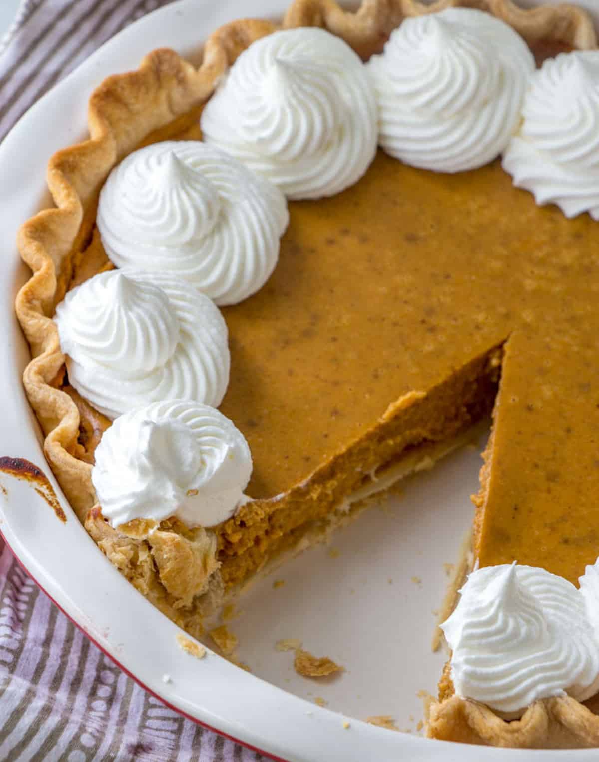 a pumpkin pie with one slice cut out