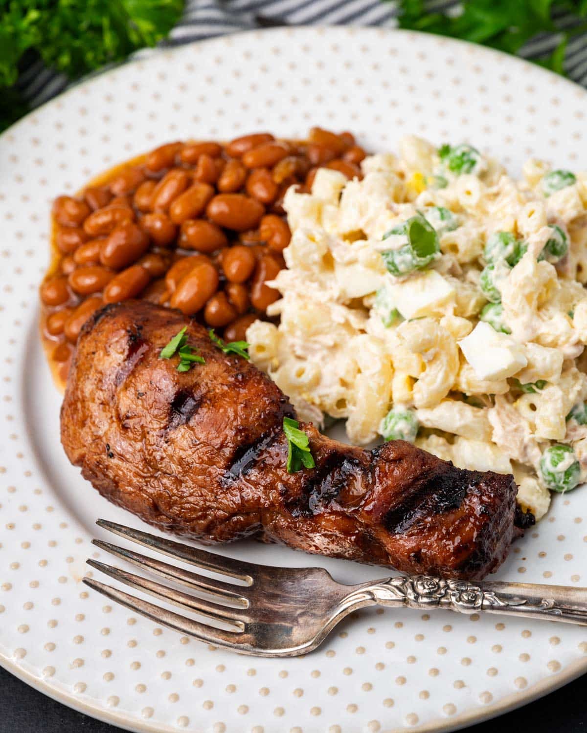 a plate of marinated spare ribs with macaroni salad and baked beans