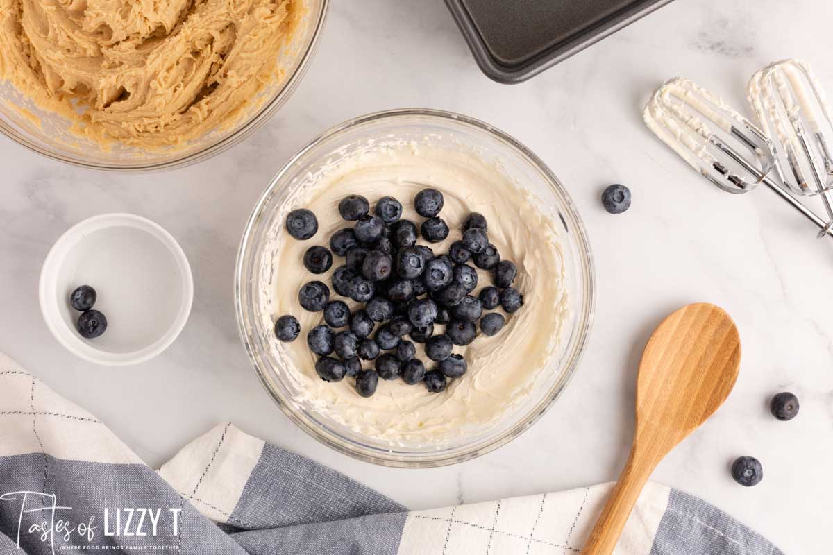 blueberries over cheesecake batter in a bowl