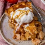 closeup of a piece of apple pie with ice cream and caramel on a plate