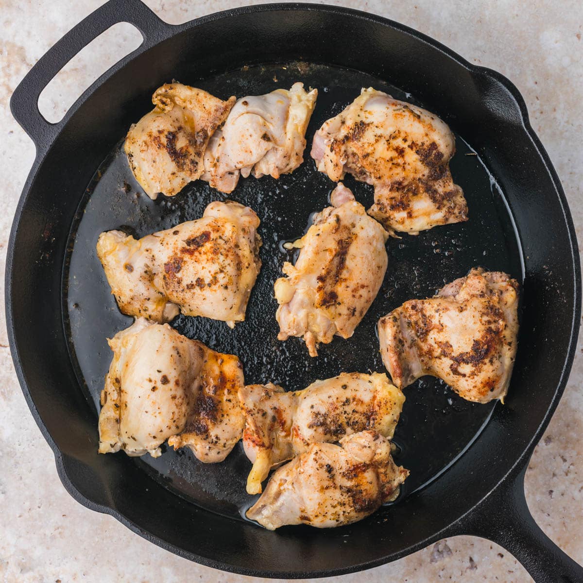 chicken thighs cooking in a cast iron skillet