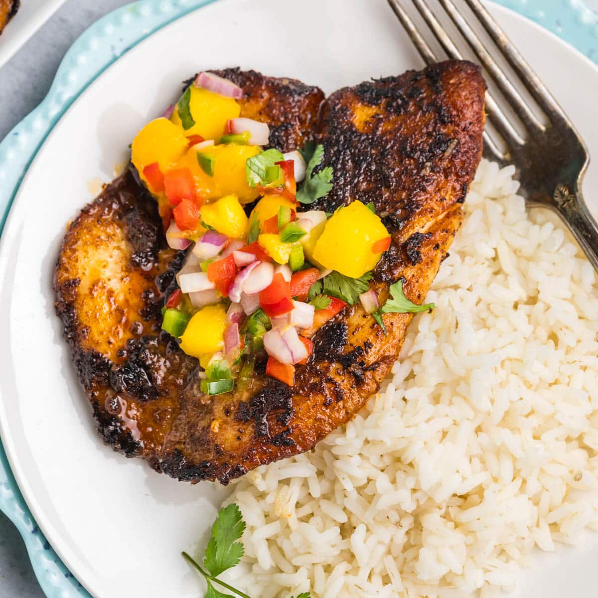 a piece of tilapia with mango salsa and rice on a plate