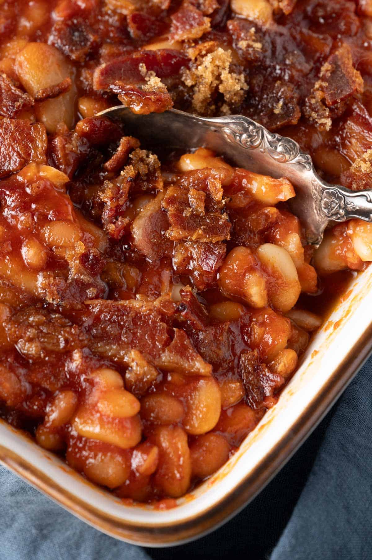 a spoon scooping up baked bean casserole with 3 beans