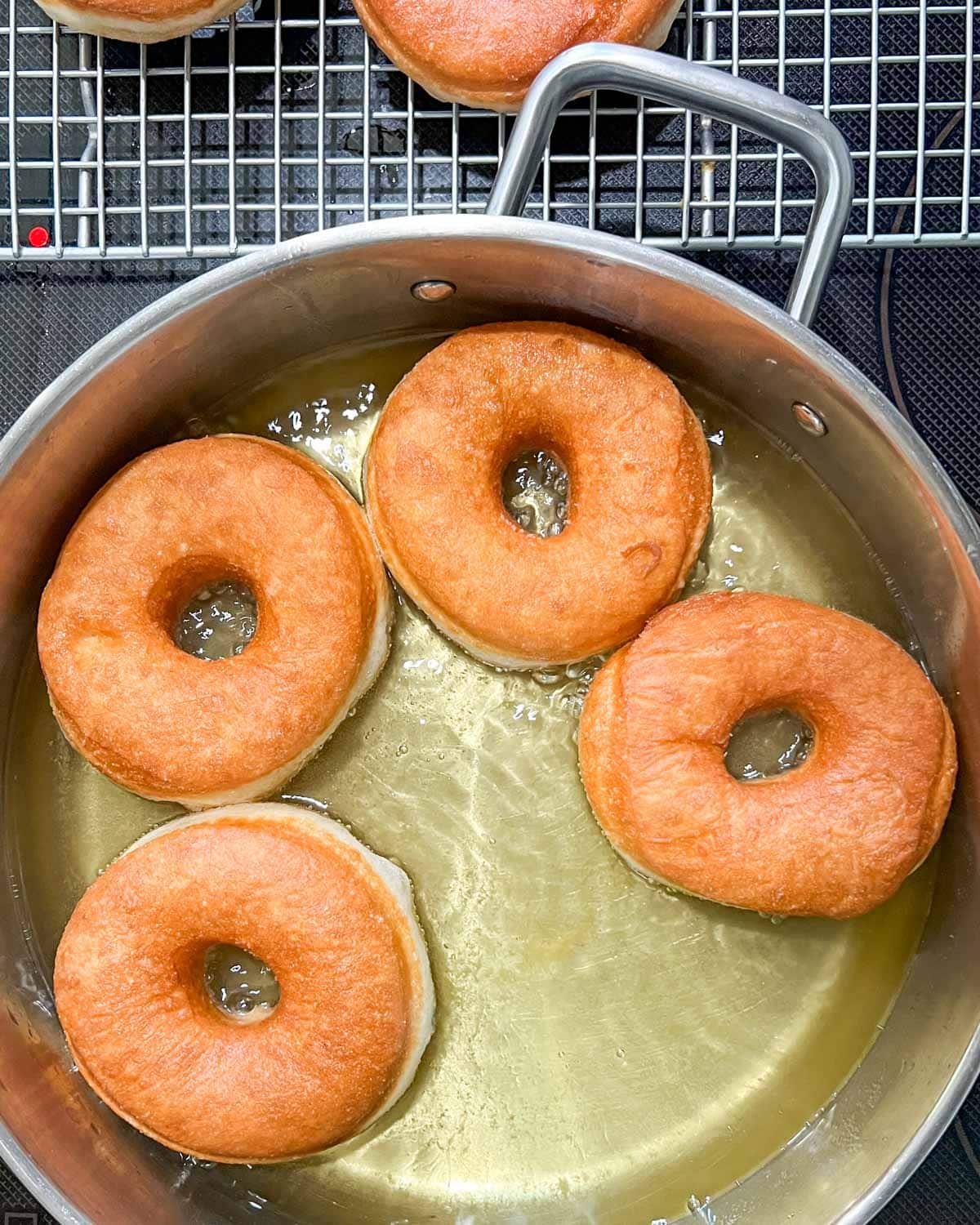 yeast donuts frying in oil in a skillet