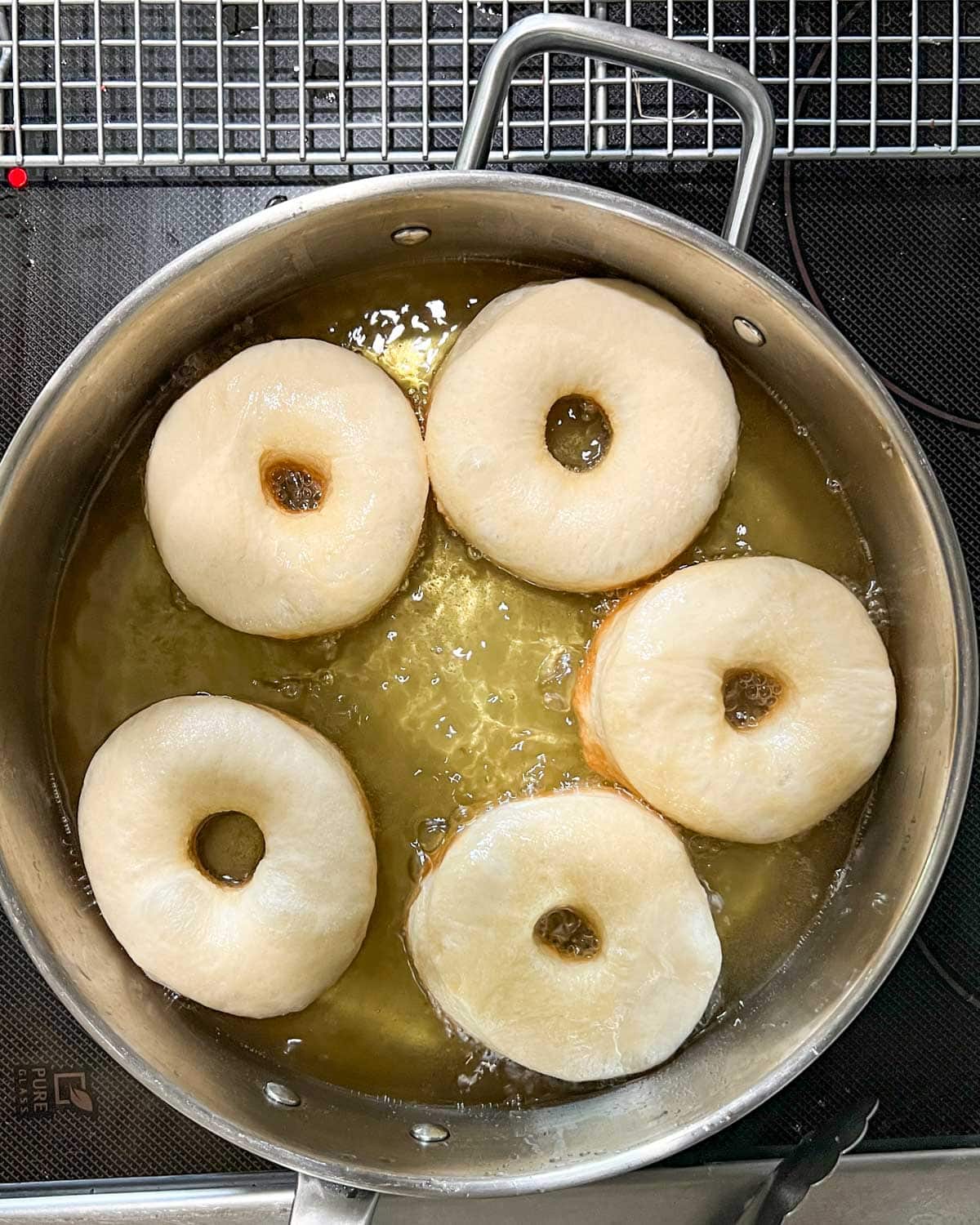 yeast donuts frying in oil in a skillet
