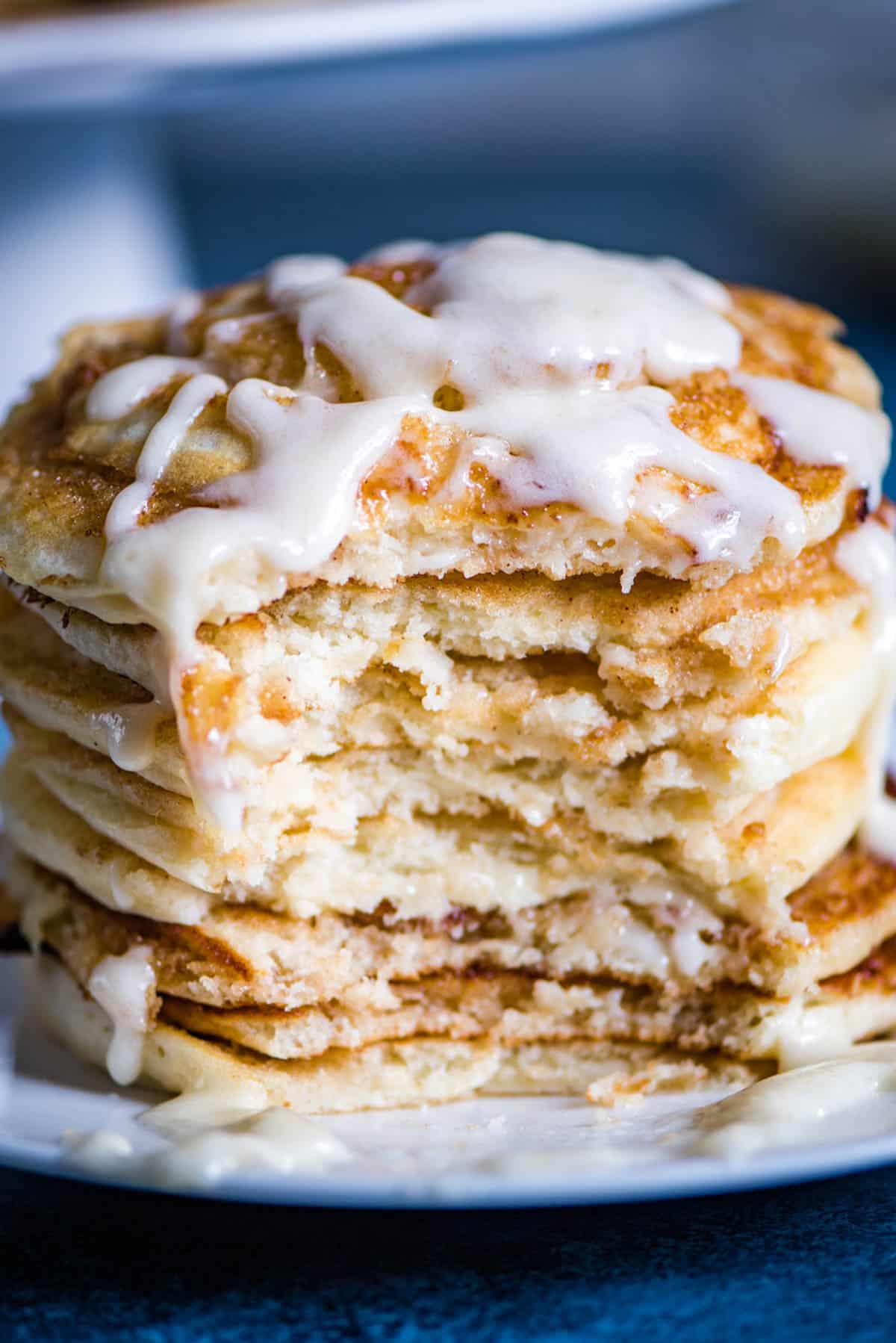 a stack of frosted cinnamon pancakes with a bite out