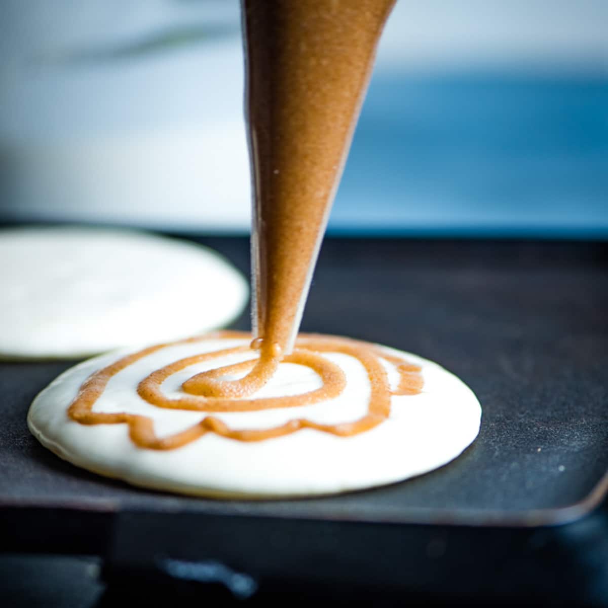 swirling cinnamon sugar on top of a pancake cooking