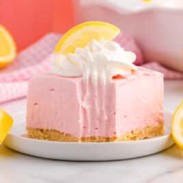 a pink lemonade pie square sitting on a plate with a fork bite out