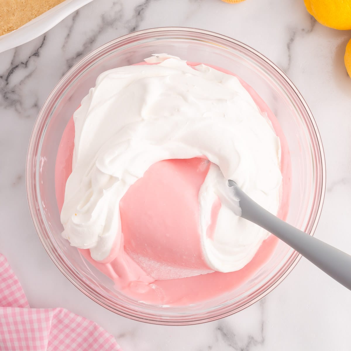 folding whipped cream into pink lemonade cheesecake batter