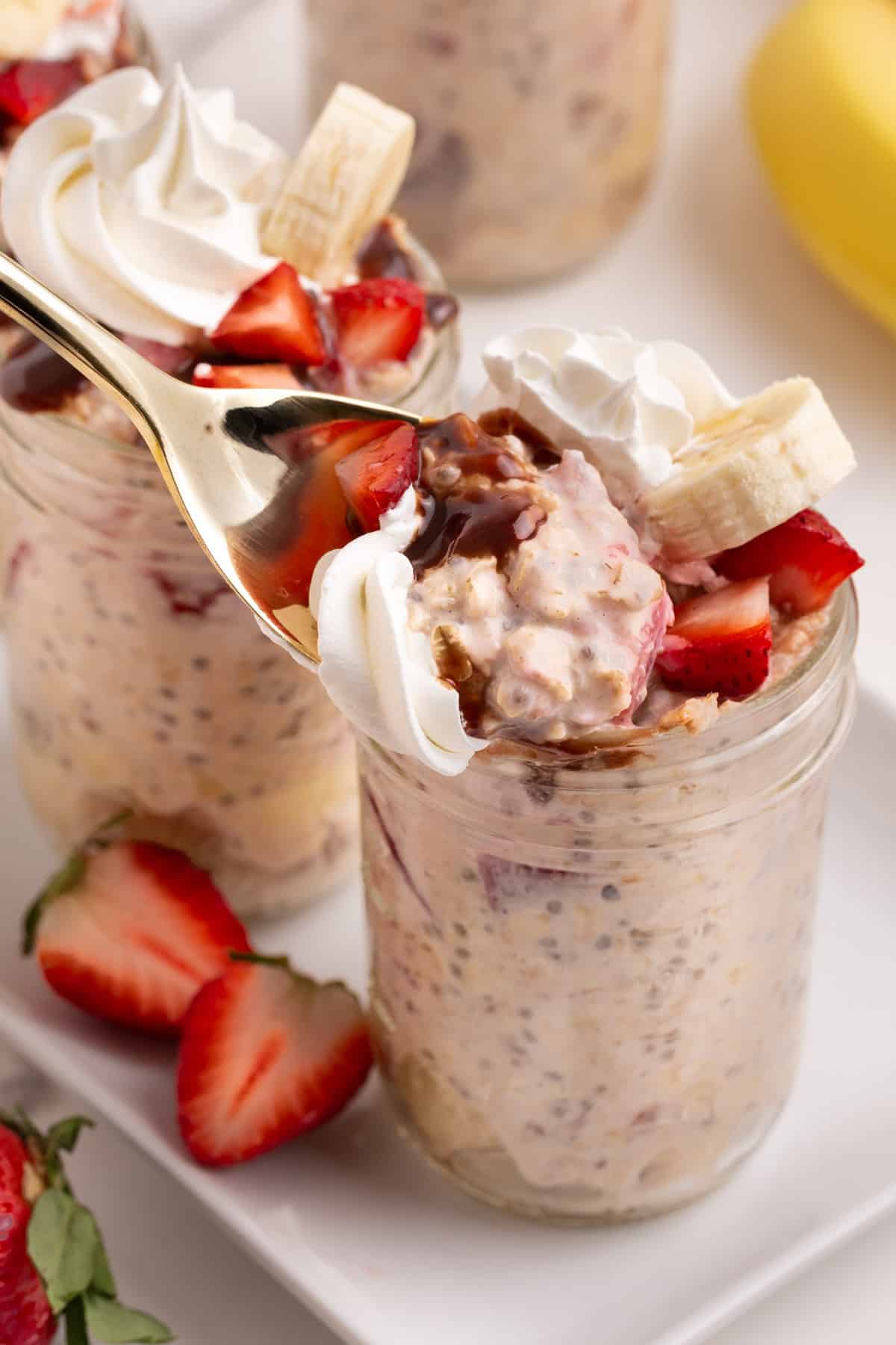overnight oats with strawberries and bananas in a mason jar with a spoon