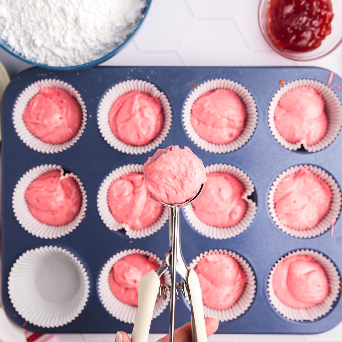 scooping strawberry cupcake batter in a cookie scoop