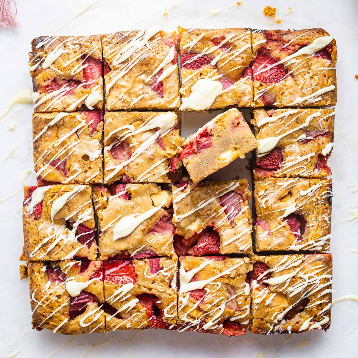 baked strawberry rhubarb blondies with white chocolate drizzled over the top