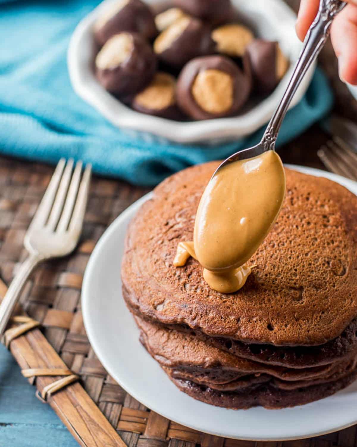 spooning peanut butter over chocolate pancakes
