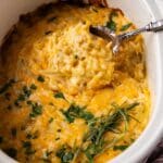 a serving spoon spooning out cheesy hashbrown casserole from a crockpot