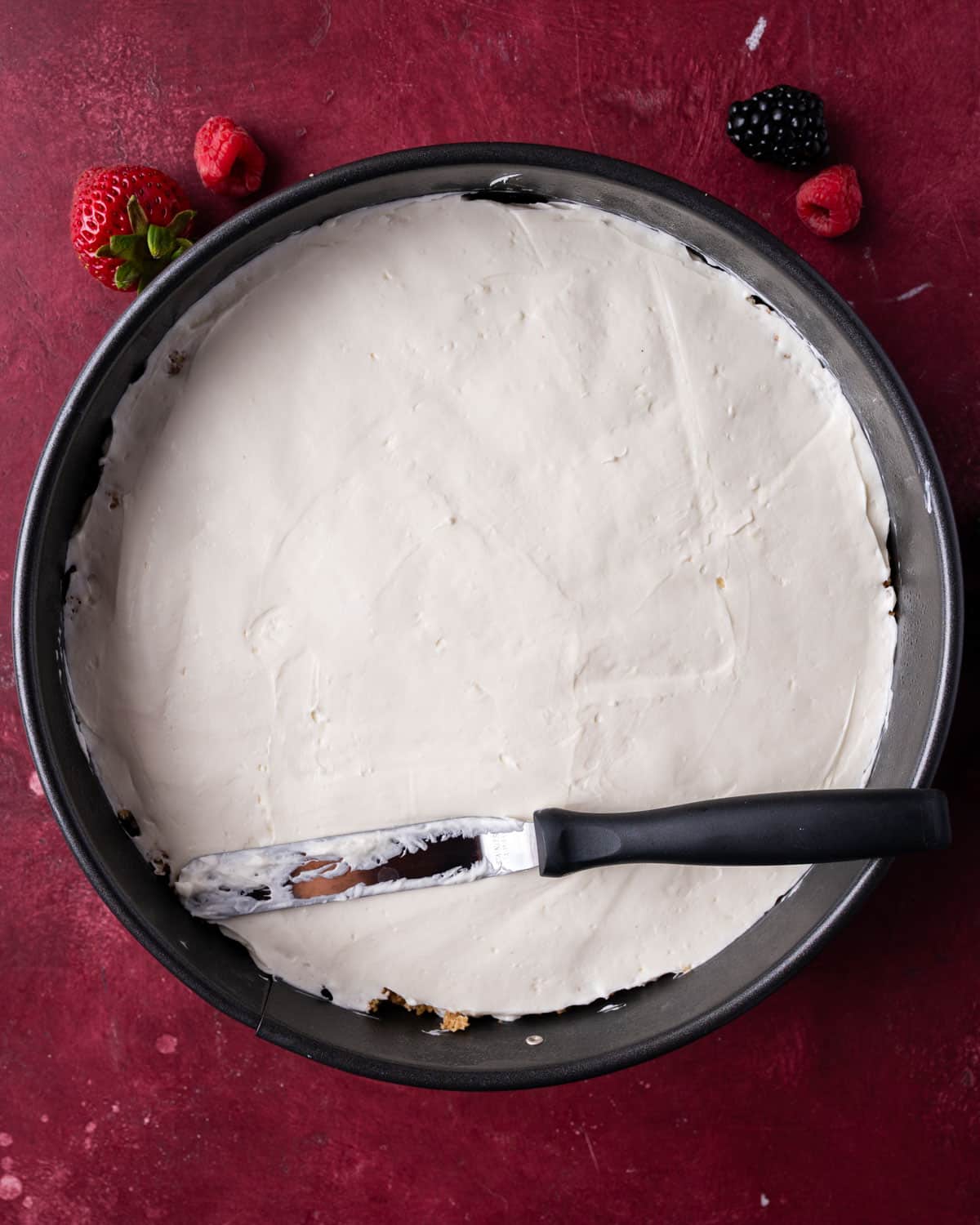 a spatula smoothing the top of a cheesecake
