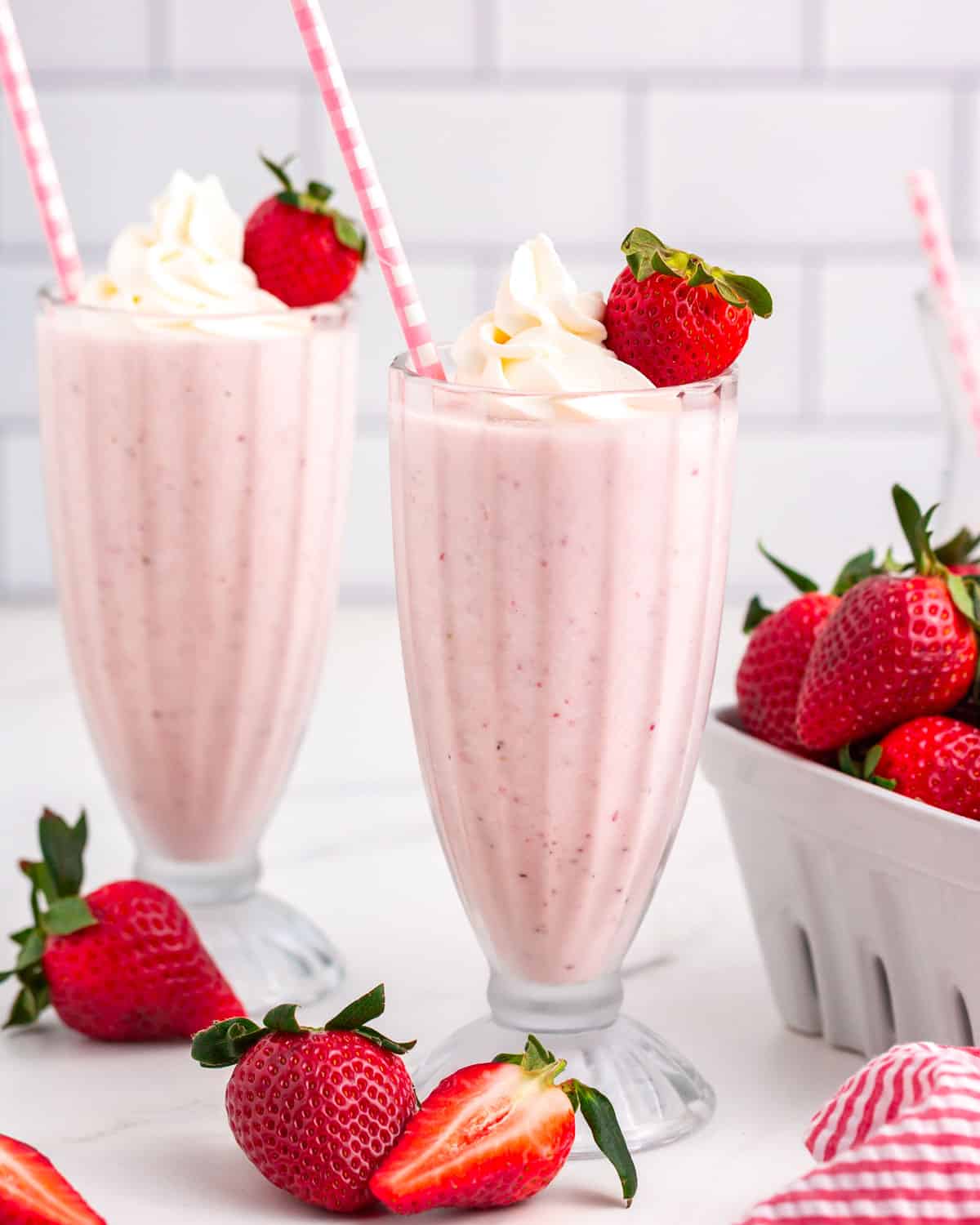strawberry milkshakes in glasses with fresh strawberries and a straw