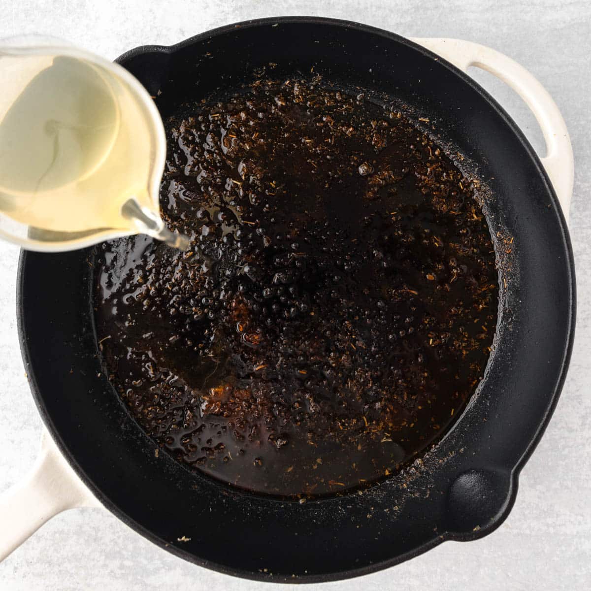 Pouring chicken broth into a skillet