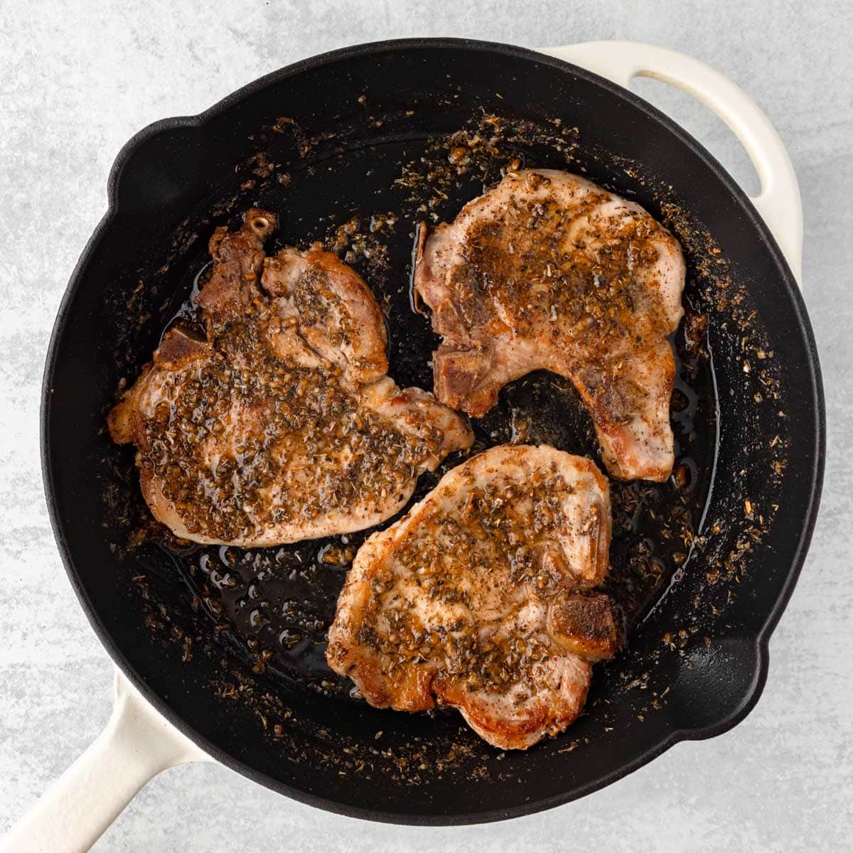 3 bone in pork chops in a cast iron skillet