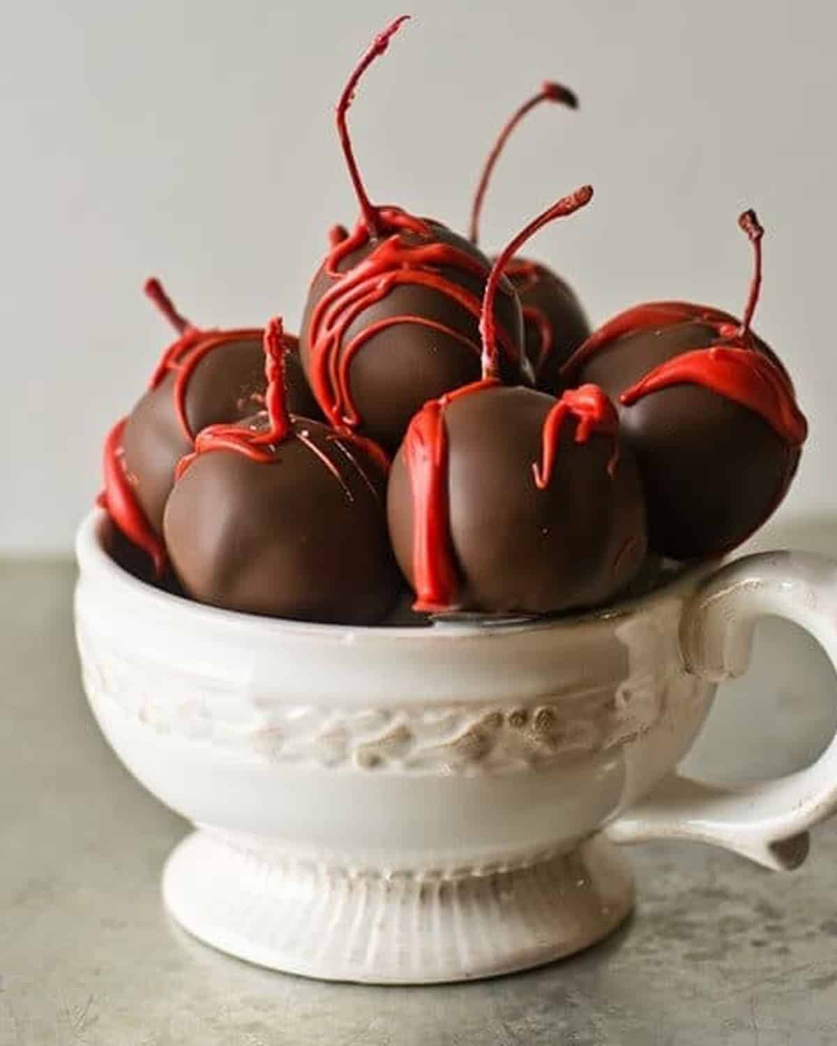 a cup of chocolate covered cherries with red drizzle