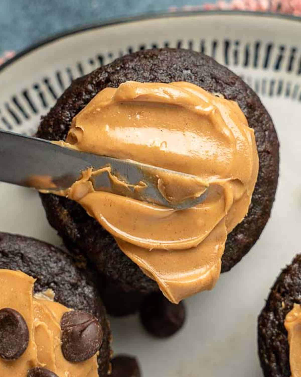 a knife spreading peanut butter on top of a muffin