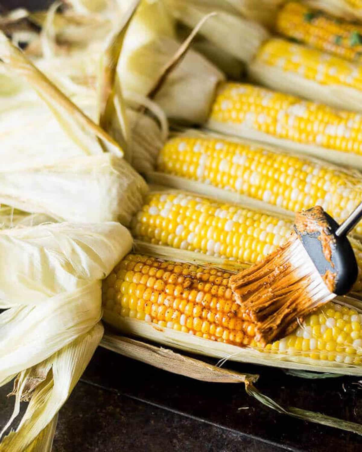 brushing chili lime butter on corn on the cob