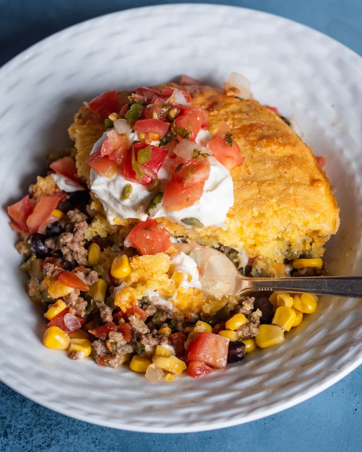 tamale pie with cornbread and ground beef on a plate with a spoon