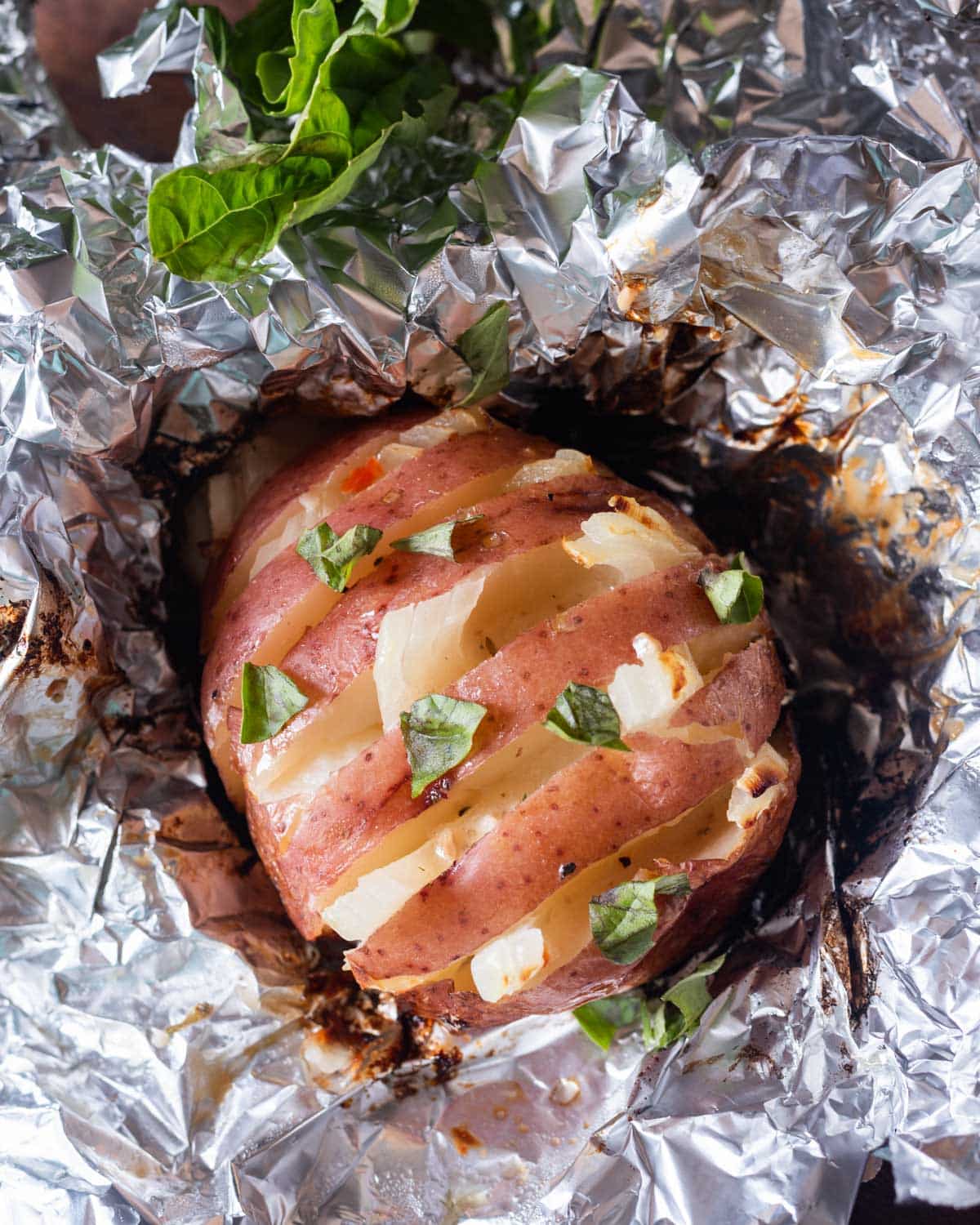 overhead view of a red potato with onion in the slices, sitting on foil