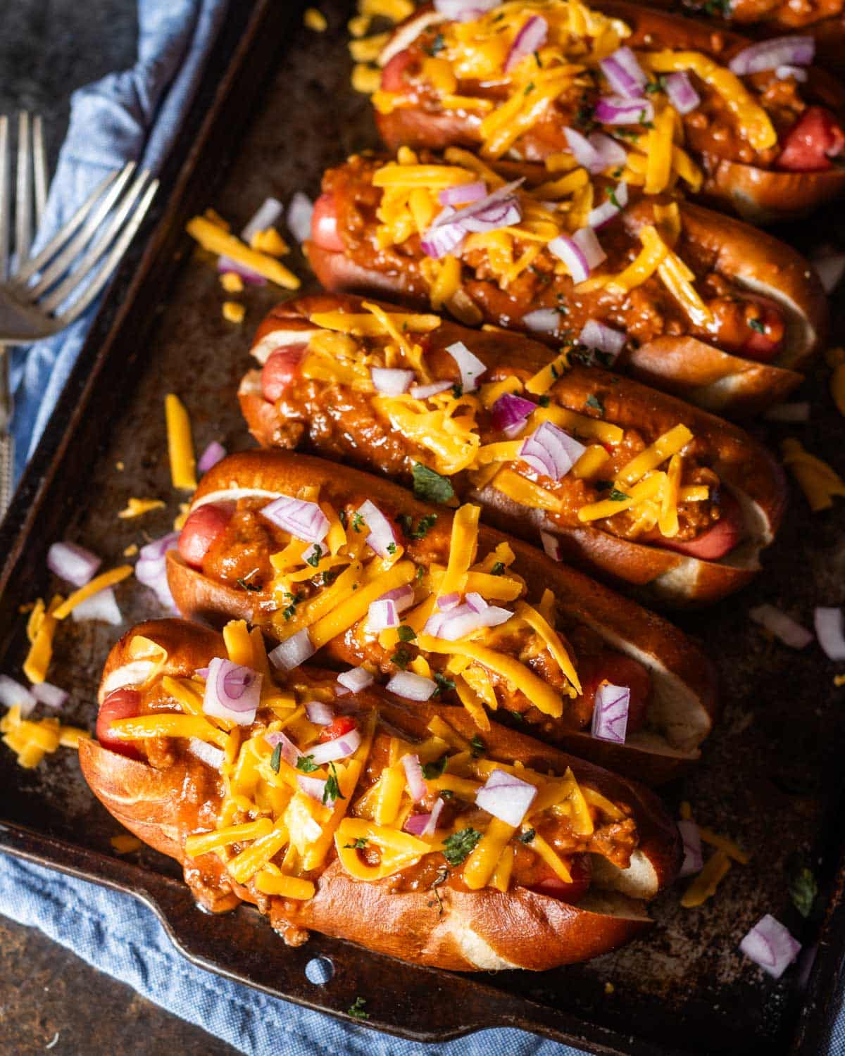 overhead view of hot dogs with chili sauce and cheese on a pan