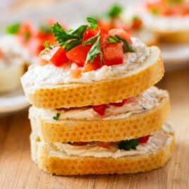 a stack of 3 mini tomato sandwiches with garlic cream cheese