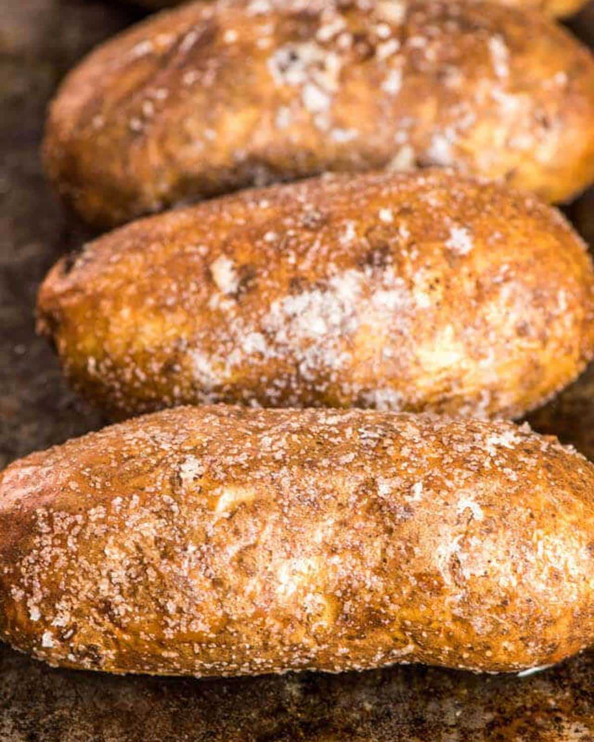 3 large baked potatoes on a baking sheet