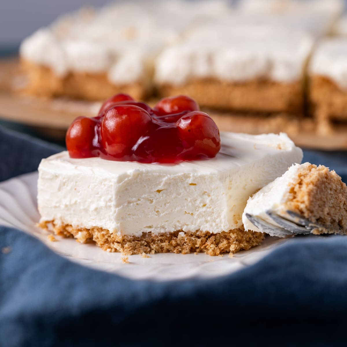 a cheesecake bar with cherries on top with one bite out