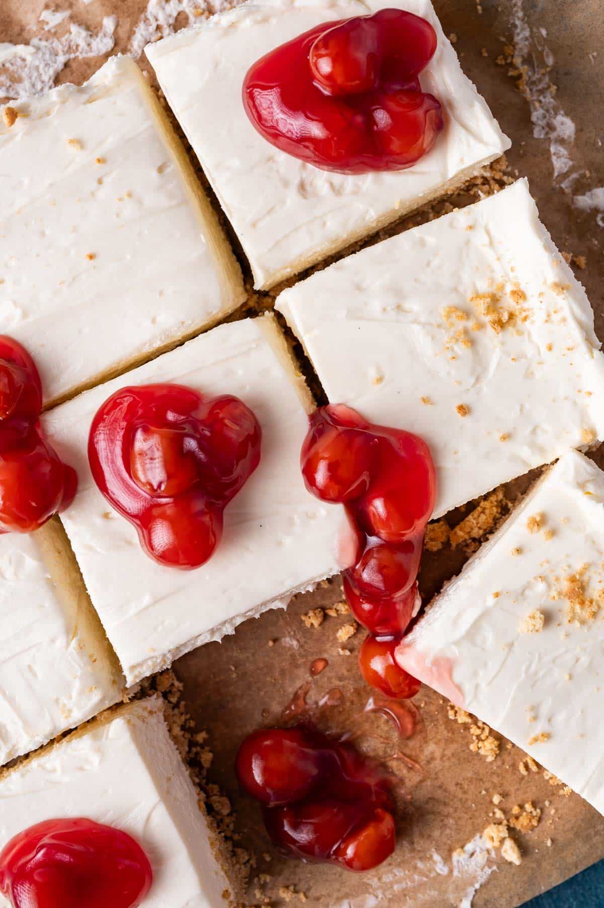 overhead view of sliced cheesecake bars with dollops of cherries