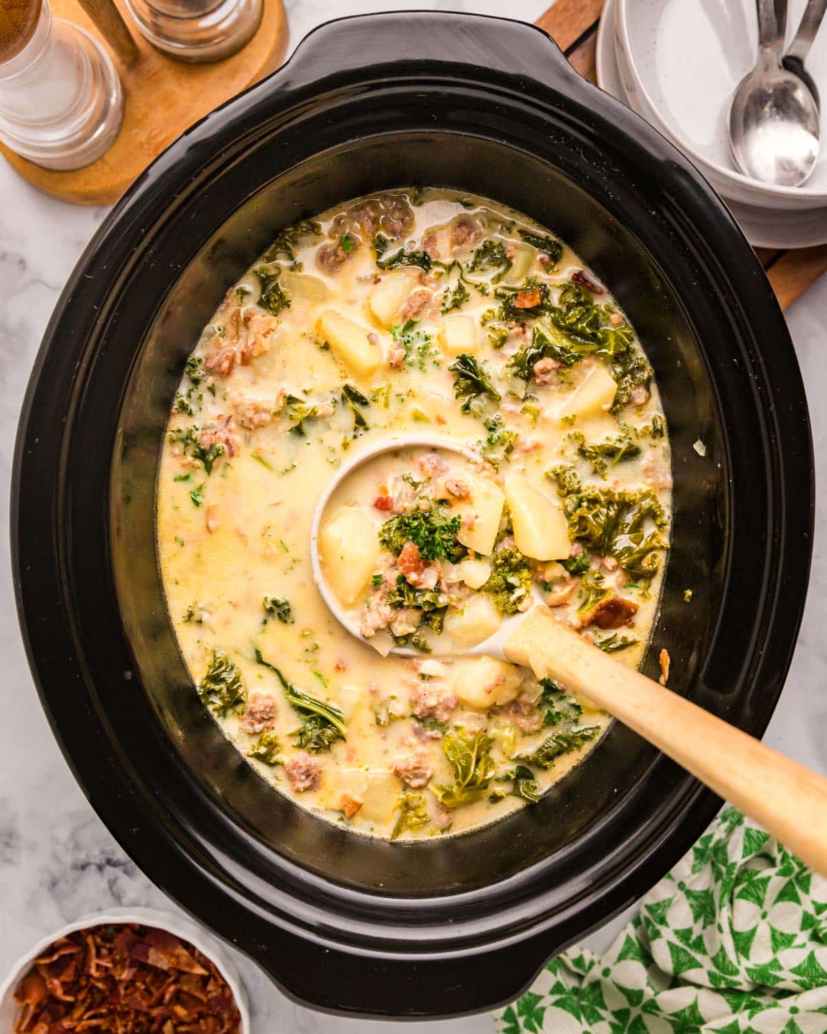 overhead view of zuppa toscana in a slow cooker with a ladle