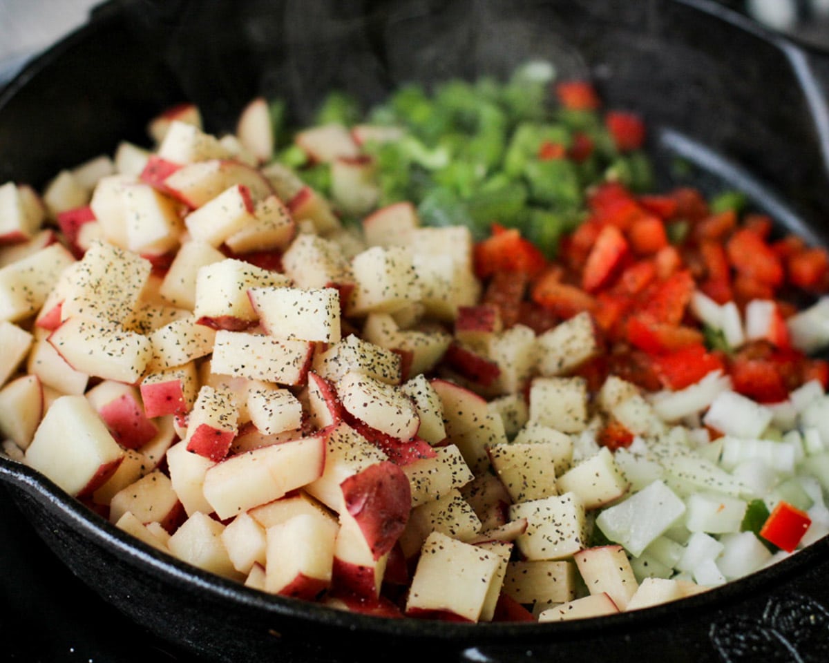 red potatoes, peppers and onions in a cast iron skillet