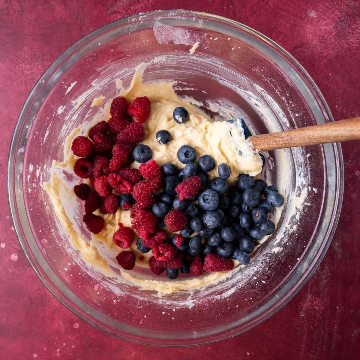 cake batter with raspberries and blueberries on it