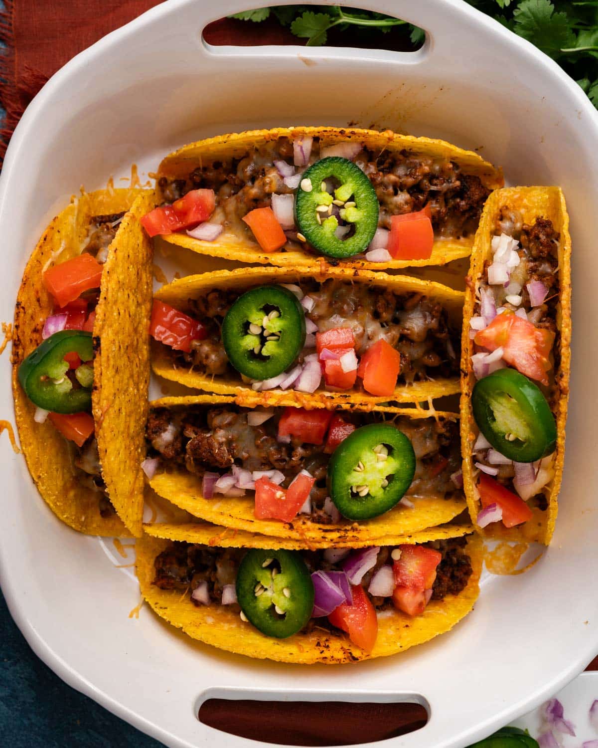 overhead view of tacos baked in a pan with fresh veggies on top