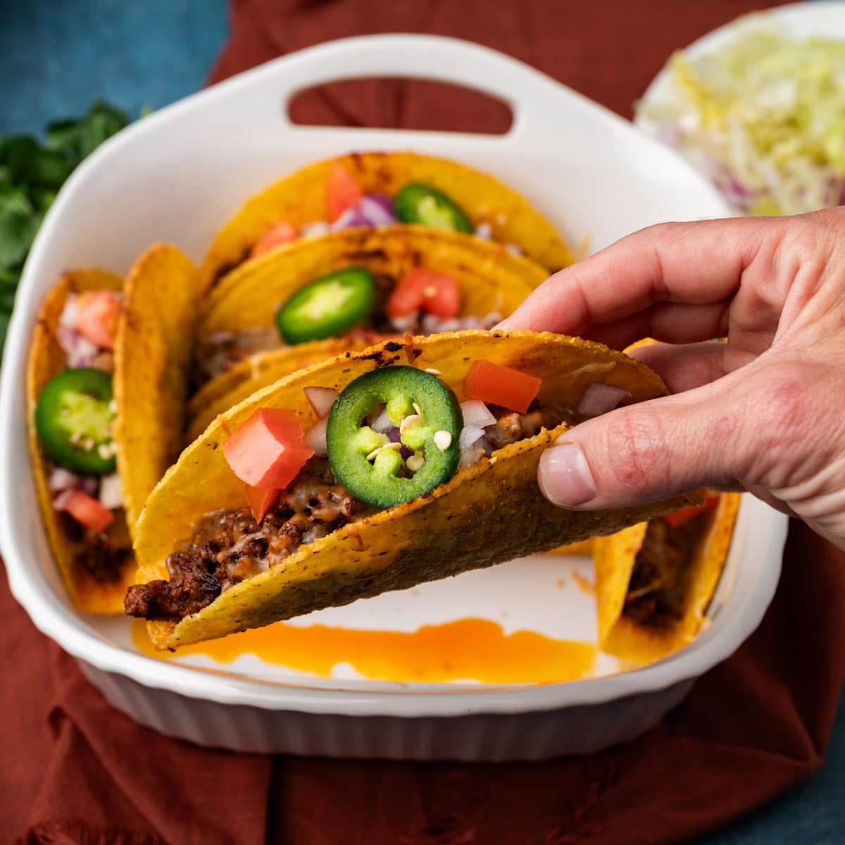 a hand holding a hard shell baked taco