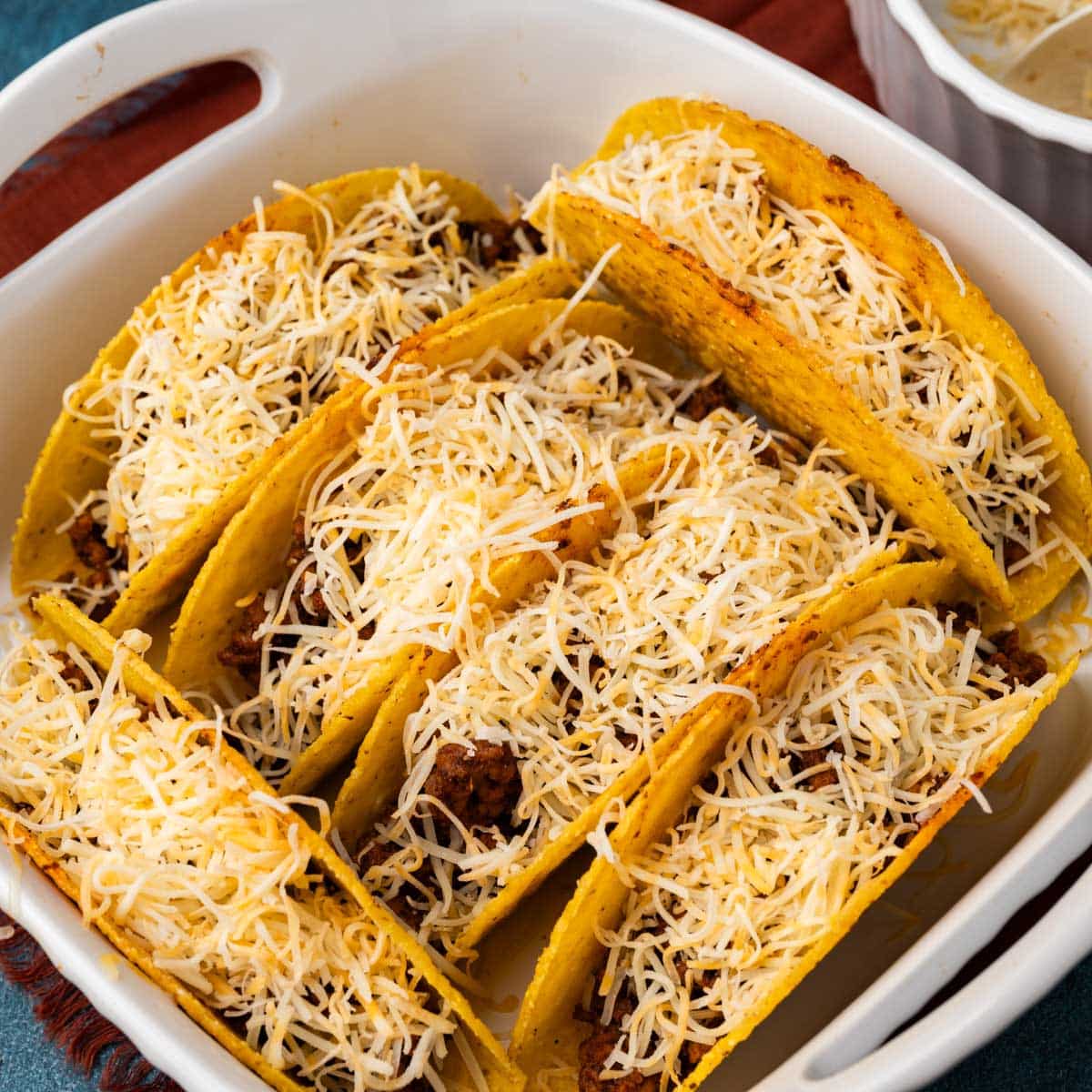 tacos with hard shells and cheese in a baking pan