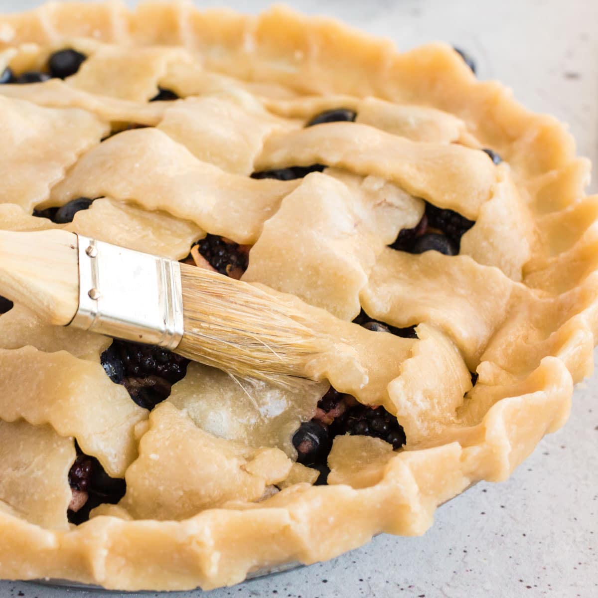 brushing egg wash over a lattice pie crust