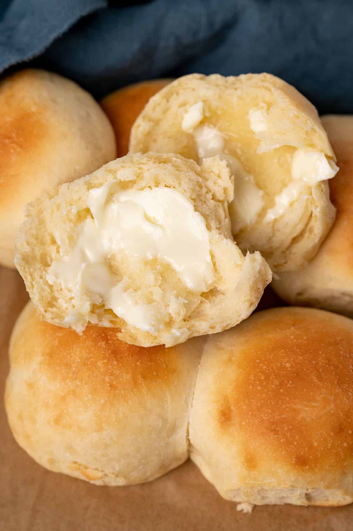 brown and serve dinner rolls on a table, one buttered