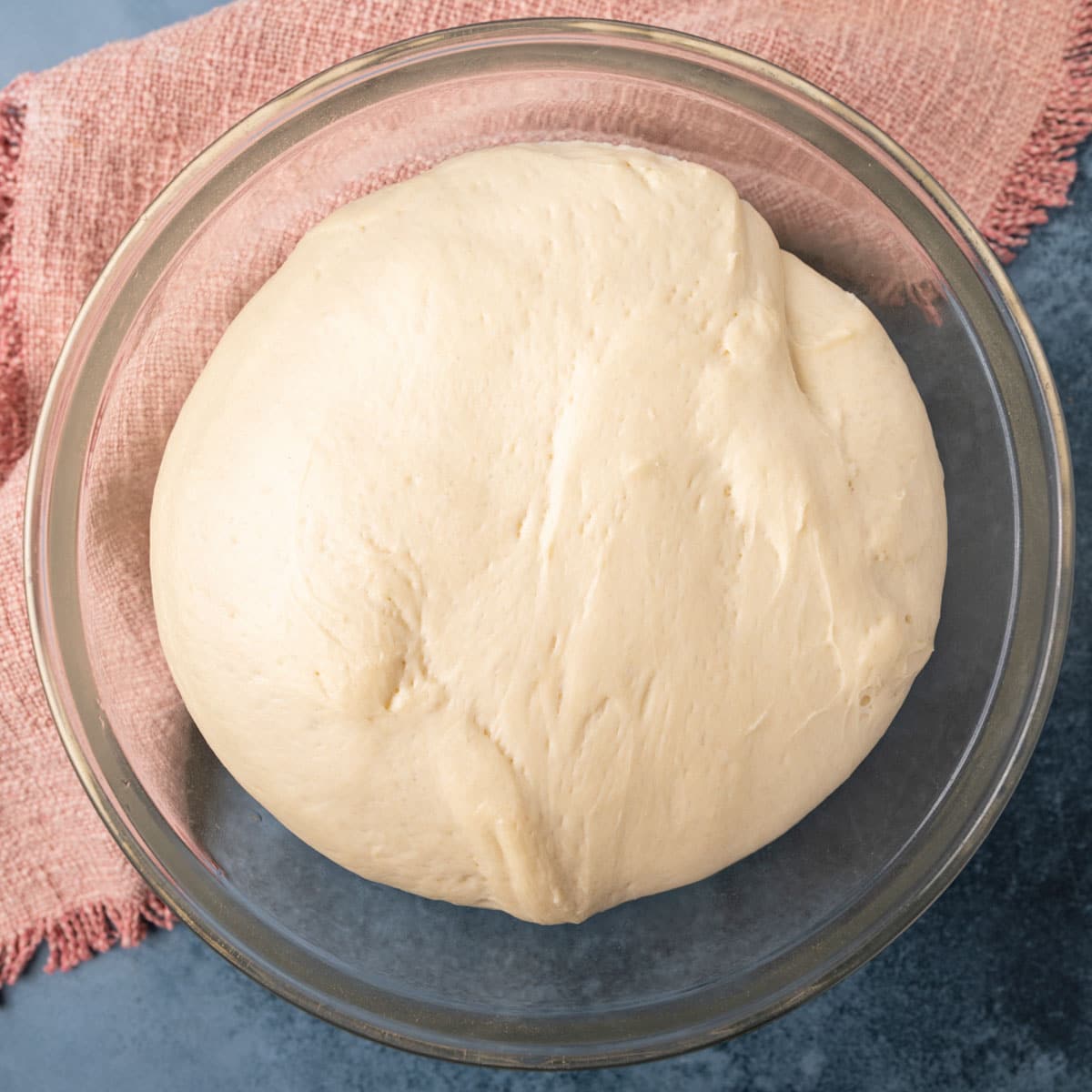 dinner roll dough risen in a glass bowl