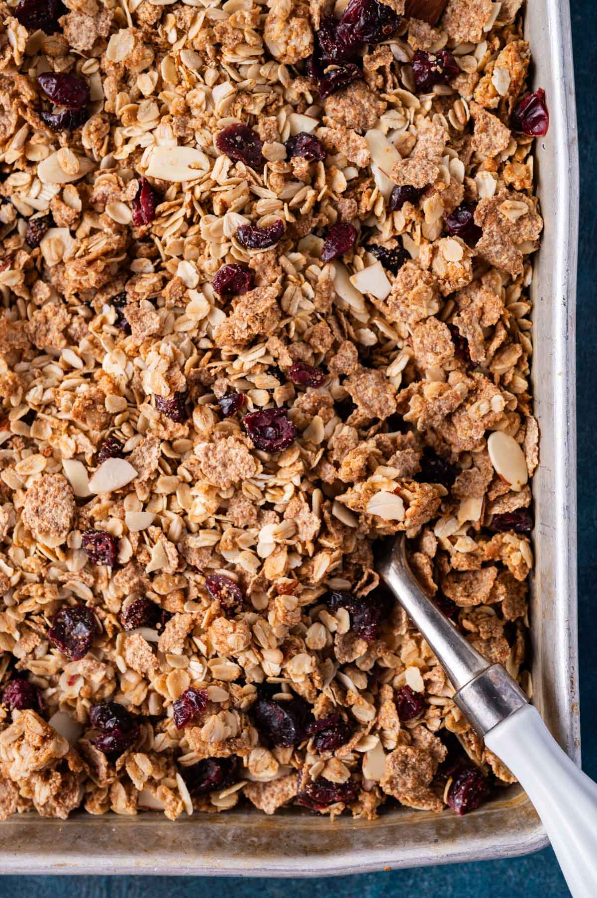 granola with almonds and cranberries in a pan with a spoon