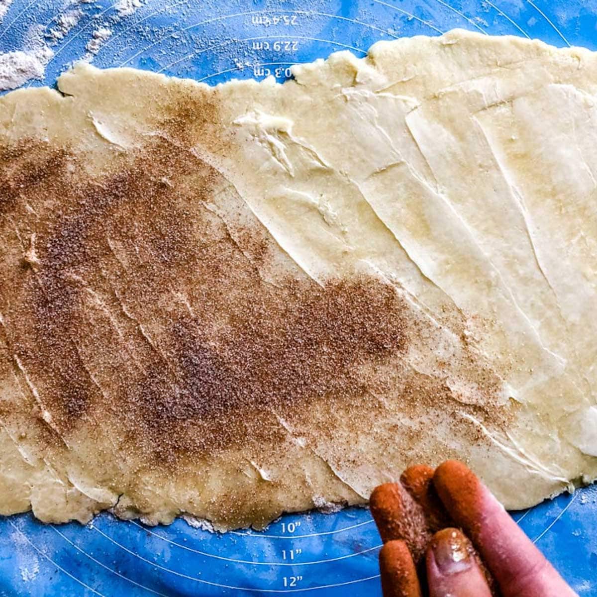 sprinkling cinnamon sugar over pie dough