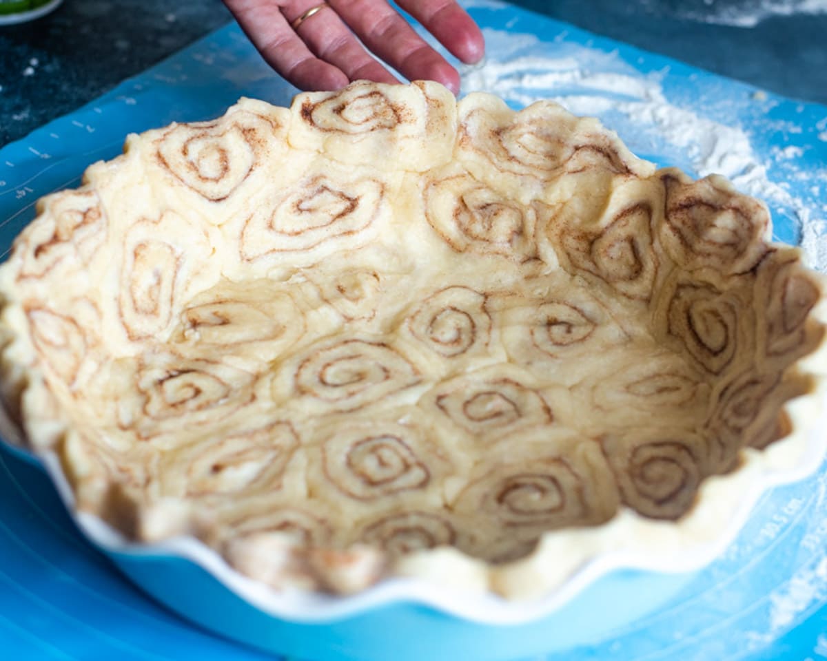 an unbaked cinnamon roll pie crust in a pie plate