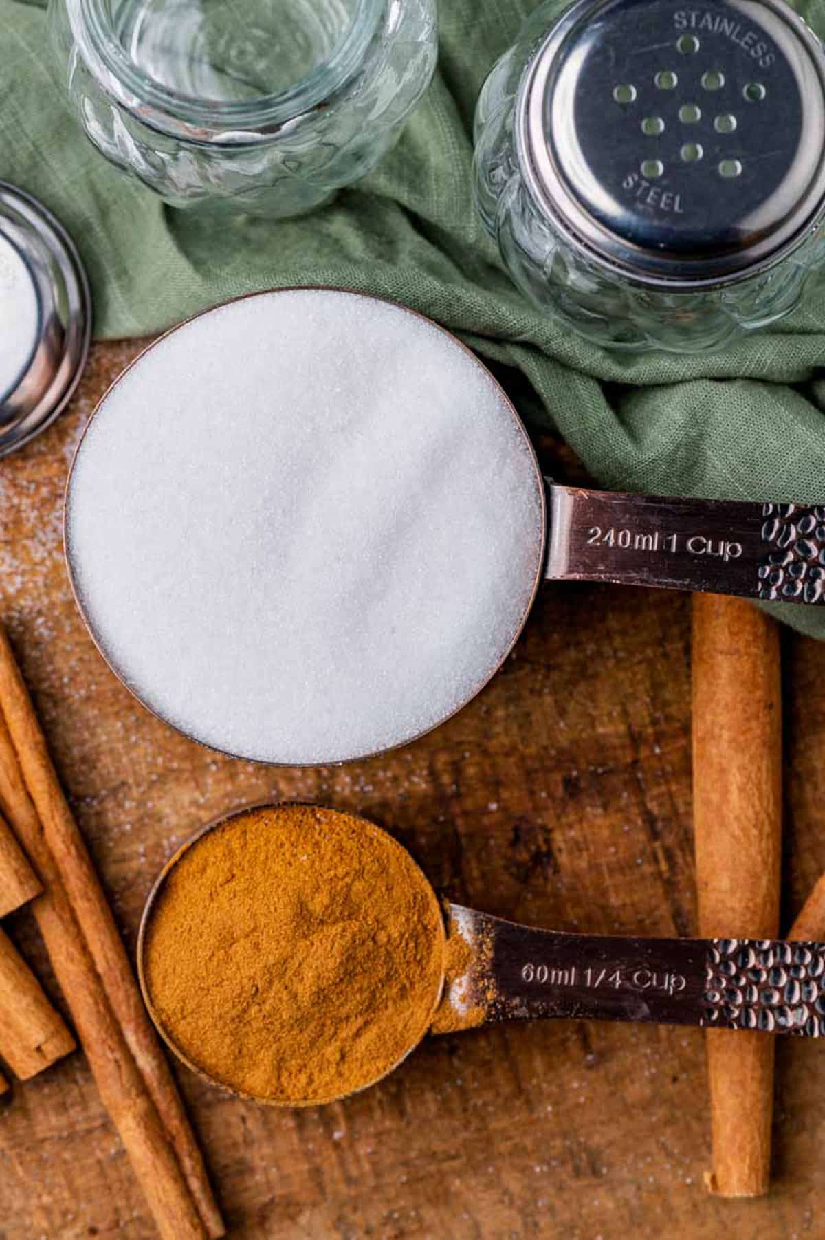 cinnamon and sugar in measuring cups on a table