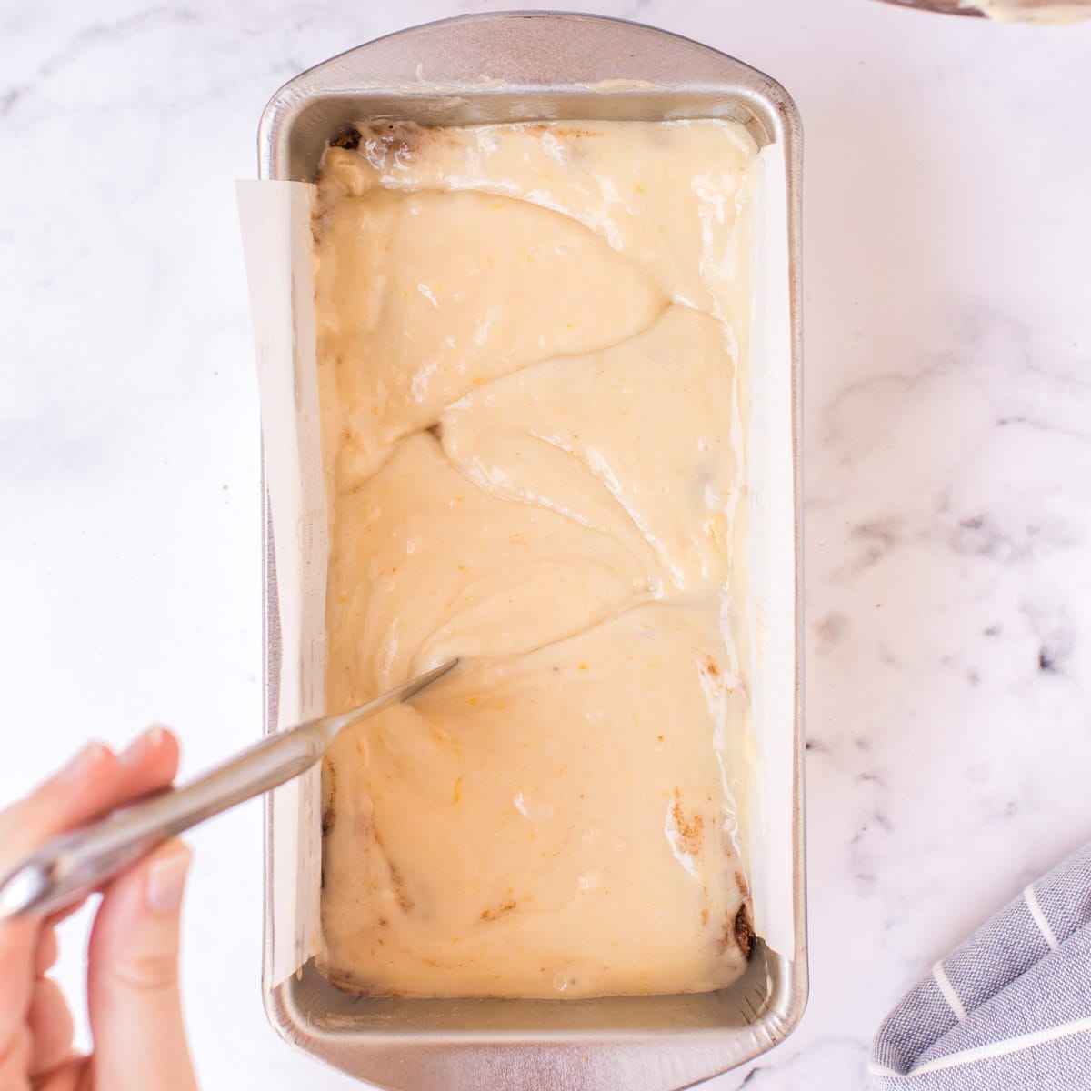 swirling cinnamon bread batter with a knife in a loaf pan