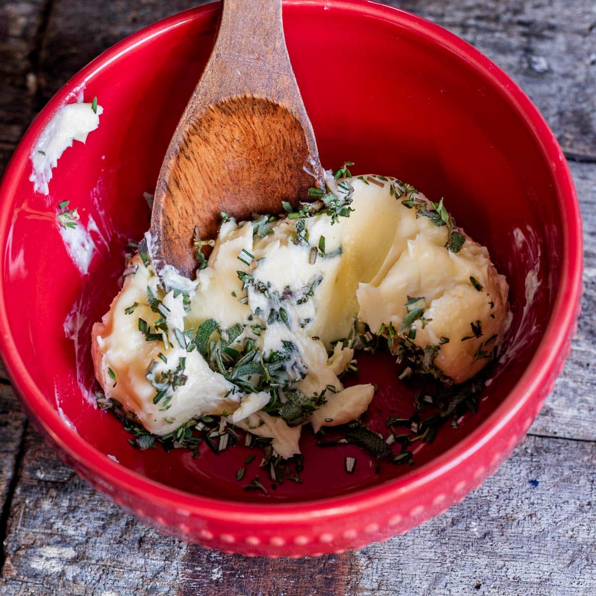 herbed butter in a red bowl with a spoon