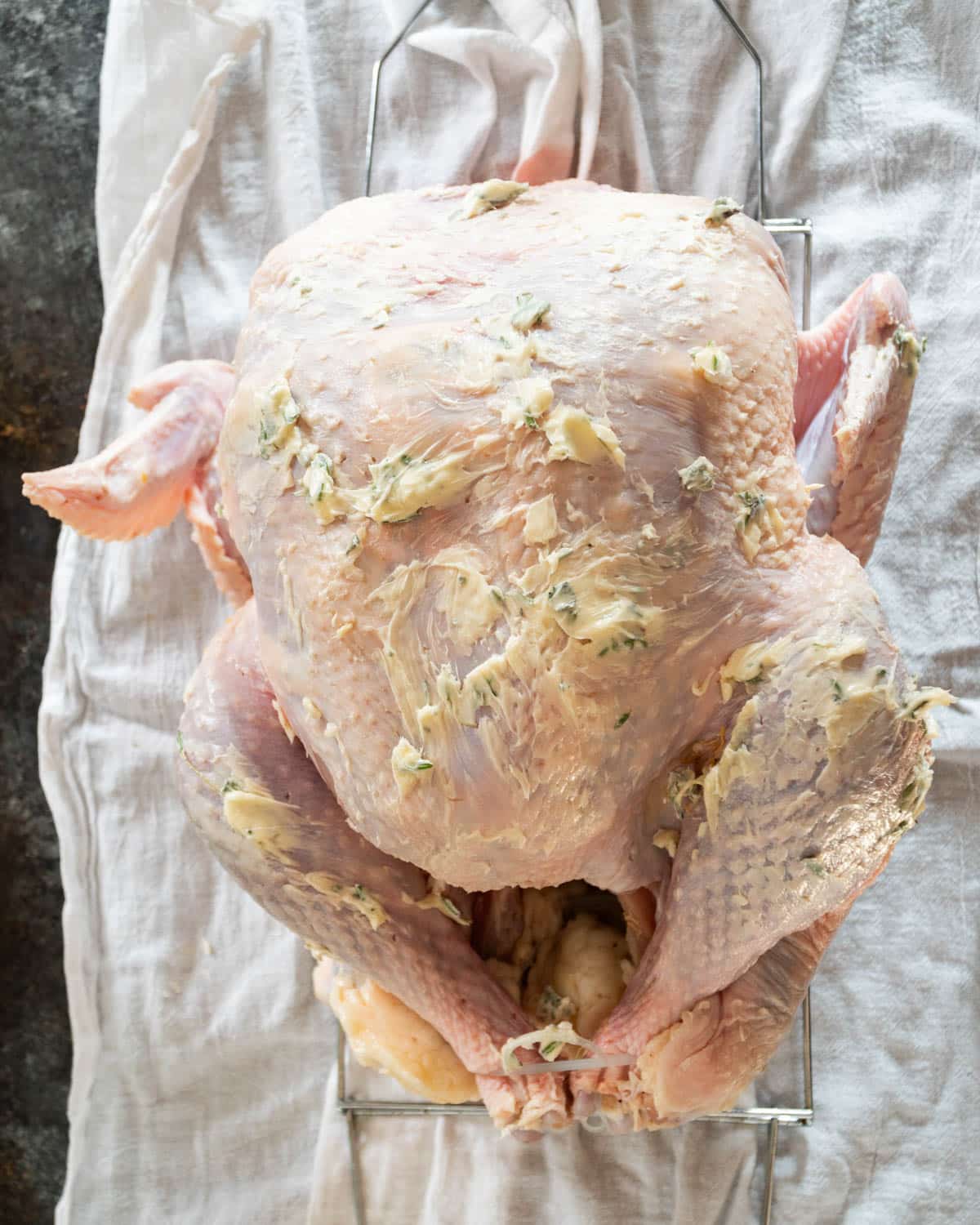 uncooked turkey with herbed butter rub on the outside