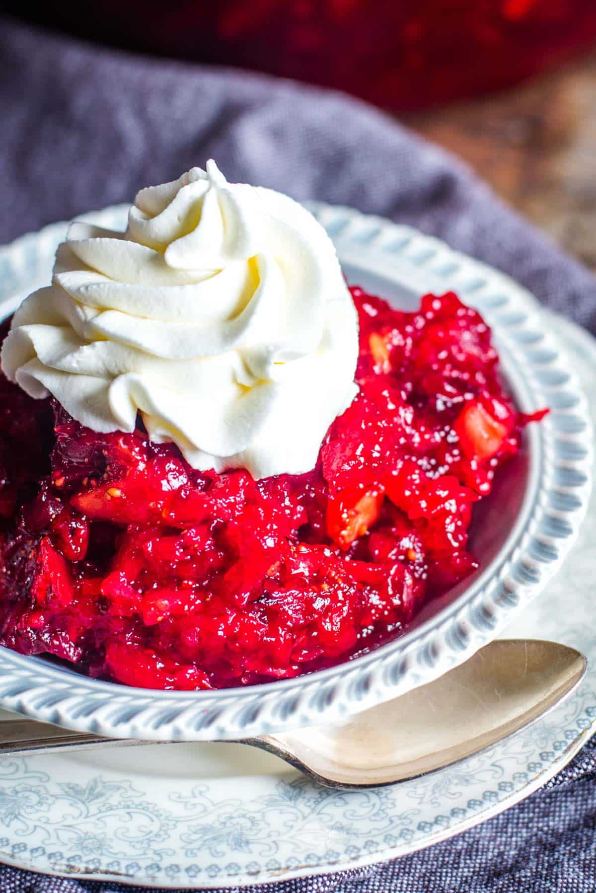 jello salad with oranges, cranberries and apples in a bowl